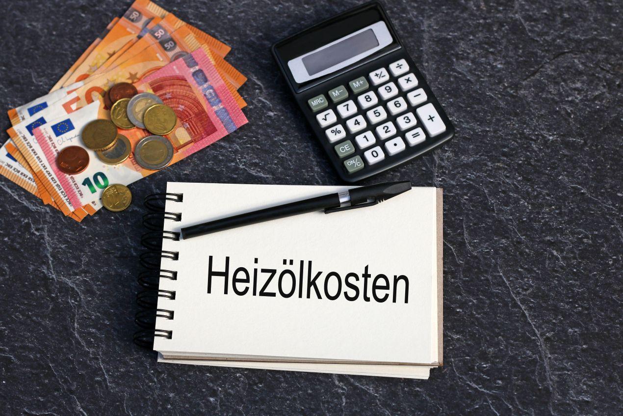 Heizölpreise Berlin im Fokus: Notizblock mit Heizölkosten, Geldscheine und Taschenrechner auf dunklem Untergrund