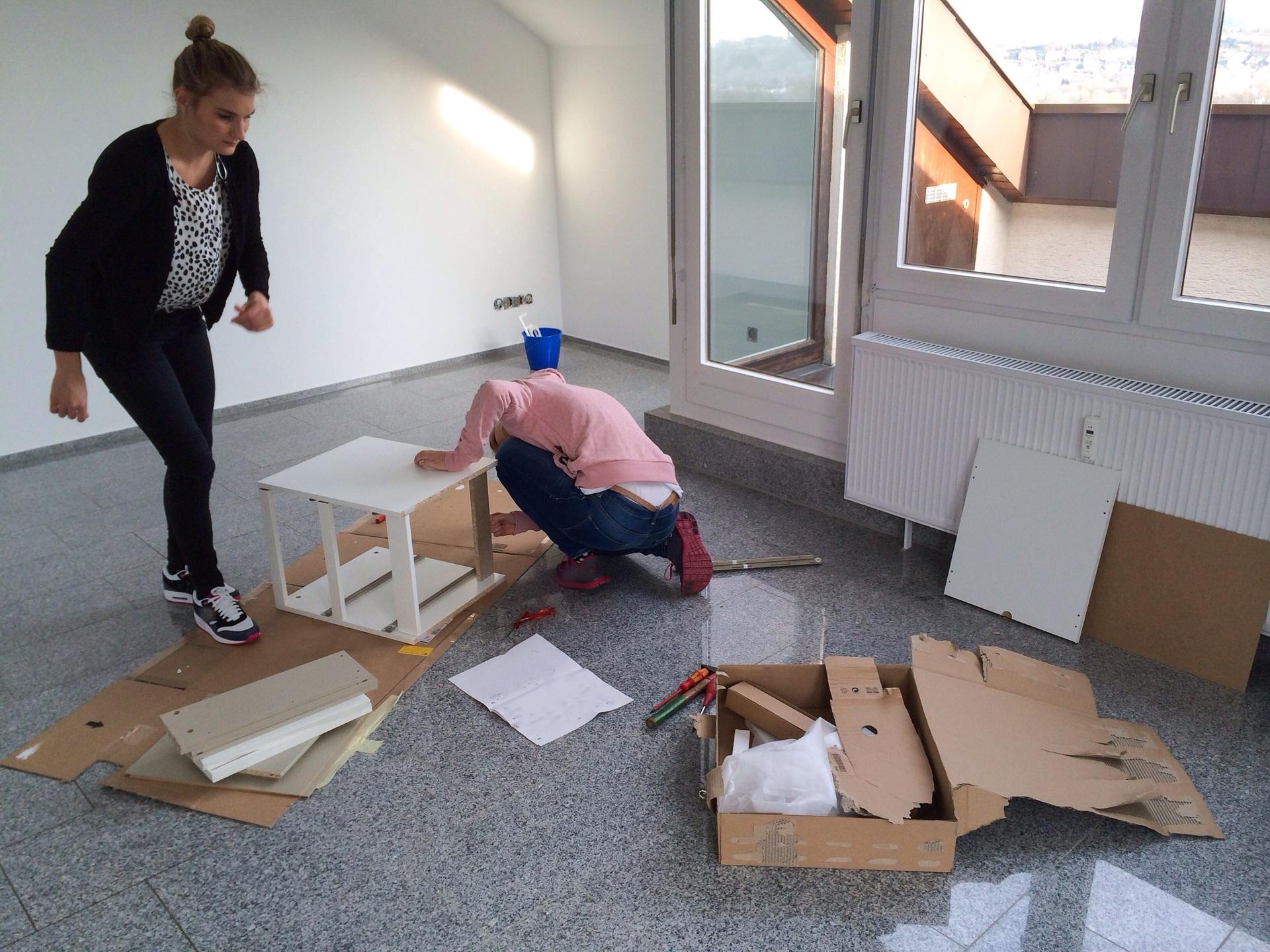 Zwei Personen bauen Möbelstück in leerer Wohnung auf | Kleiderschrank mit Spiegel