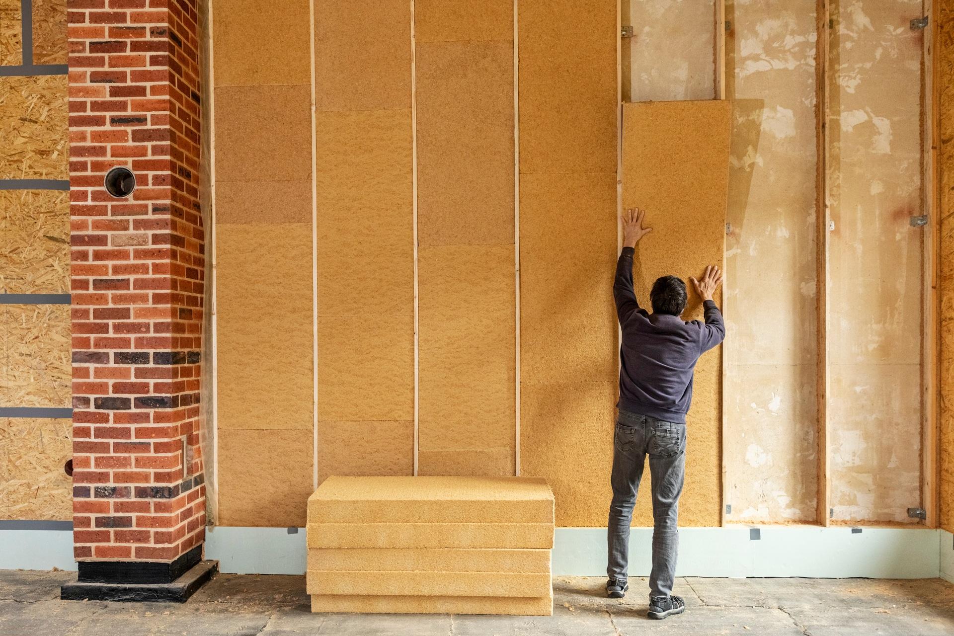 Handwerker bringt Daemmplatten an Innenwand eines Hauses an | Photovoltaik Leipzig